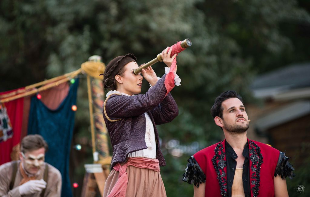 Girl looking through a telescope with a guy who looks at sky next to her
