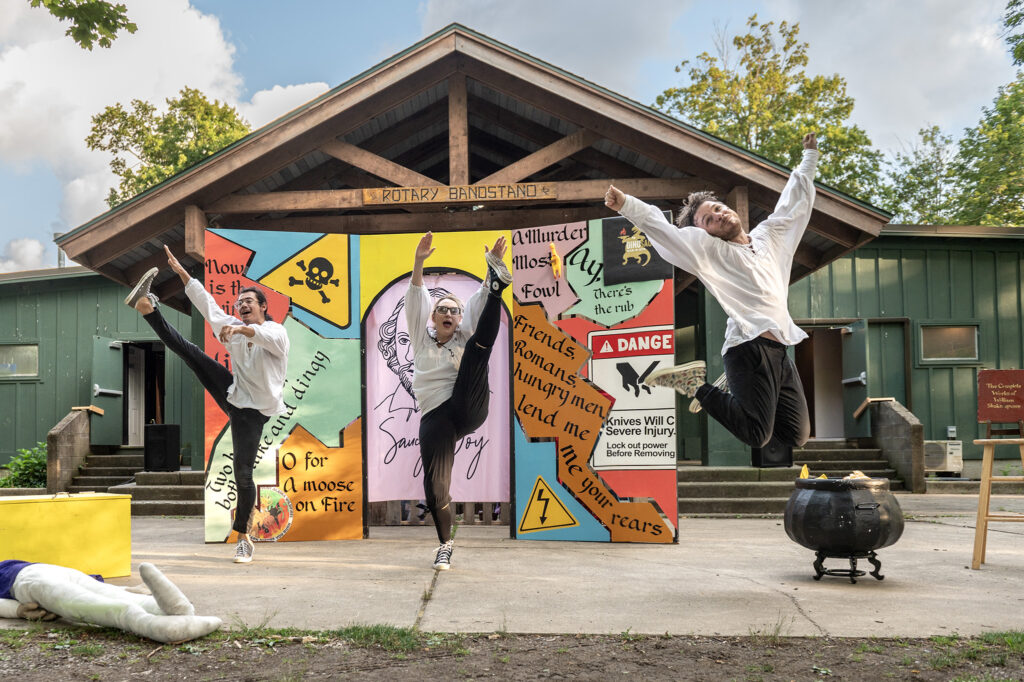 Three people jumping in front of a theater set